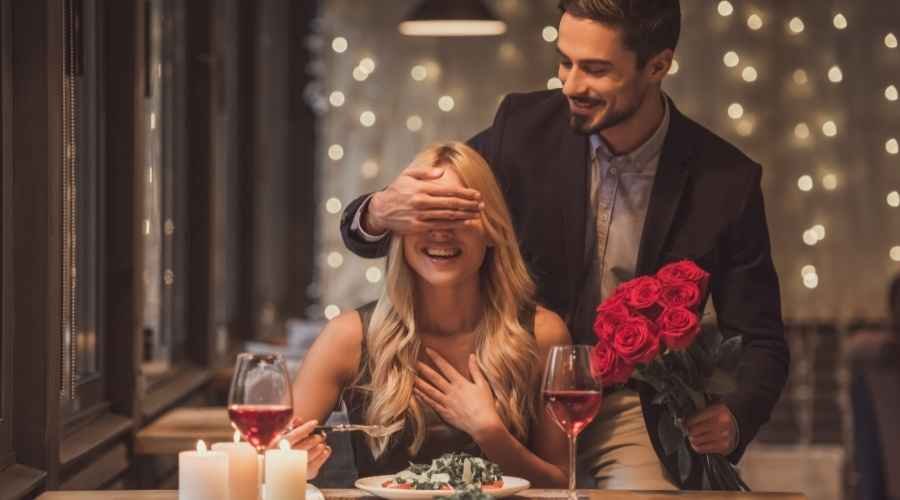 guy closing lady's eyes with hand while holding a bouqet of roses